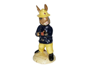 The bunny is wearing yellow trousers, a yellow firemen's helmet and a blue jacket. He is holding a fire nozzle with the hose attached.